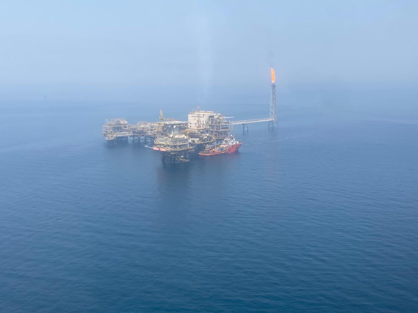 Offshore oil and gas production platform with flare stack operating at sea