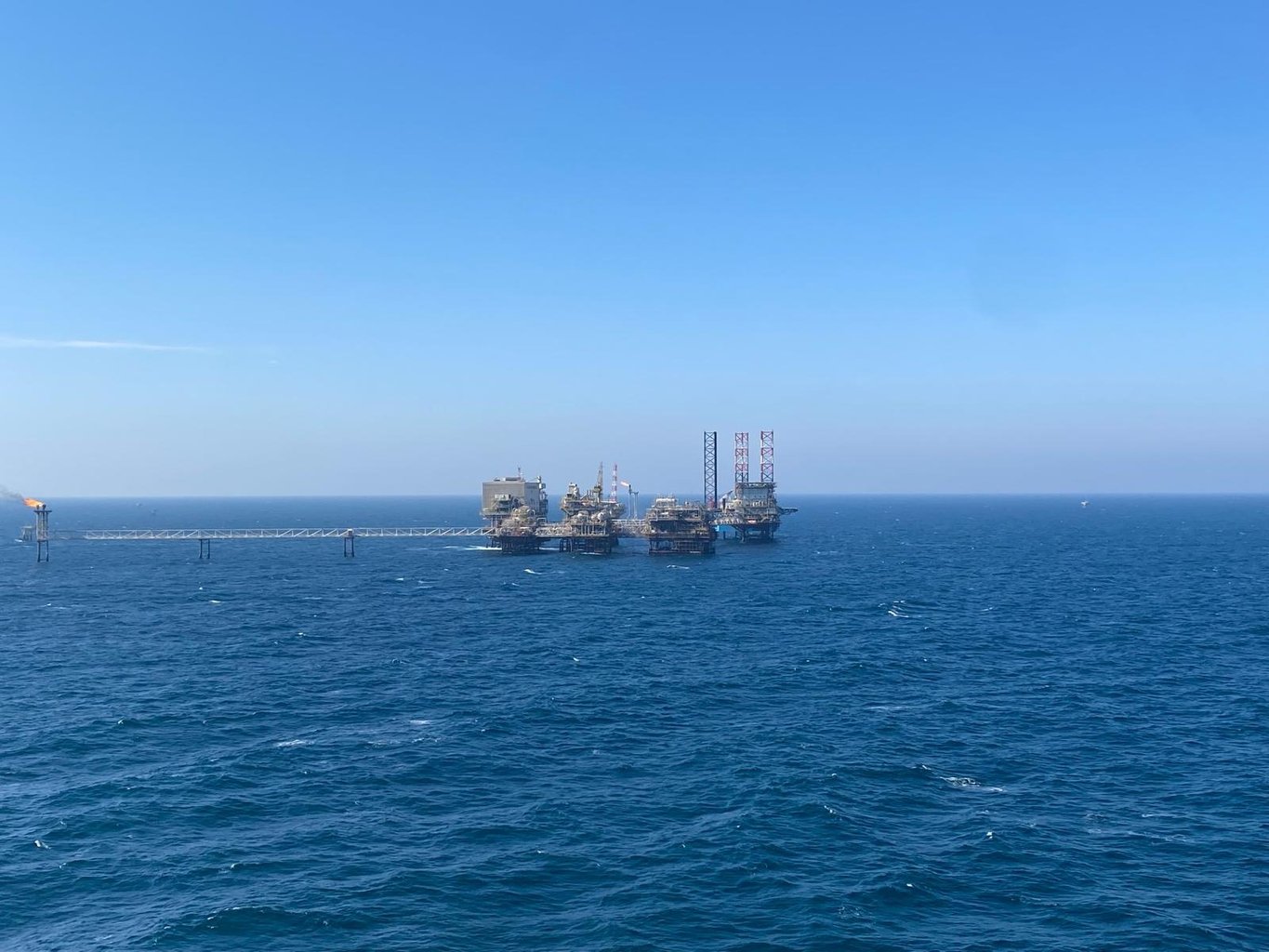 Offshore oil and gas platform complex with jack-up rig in open water